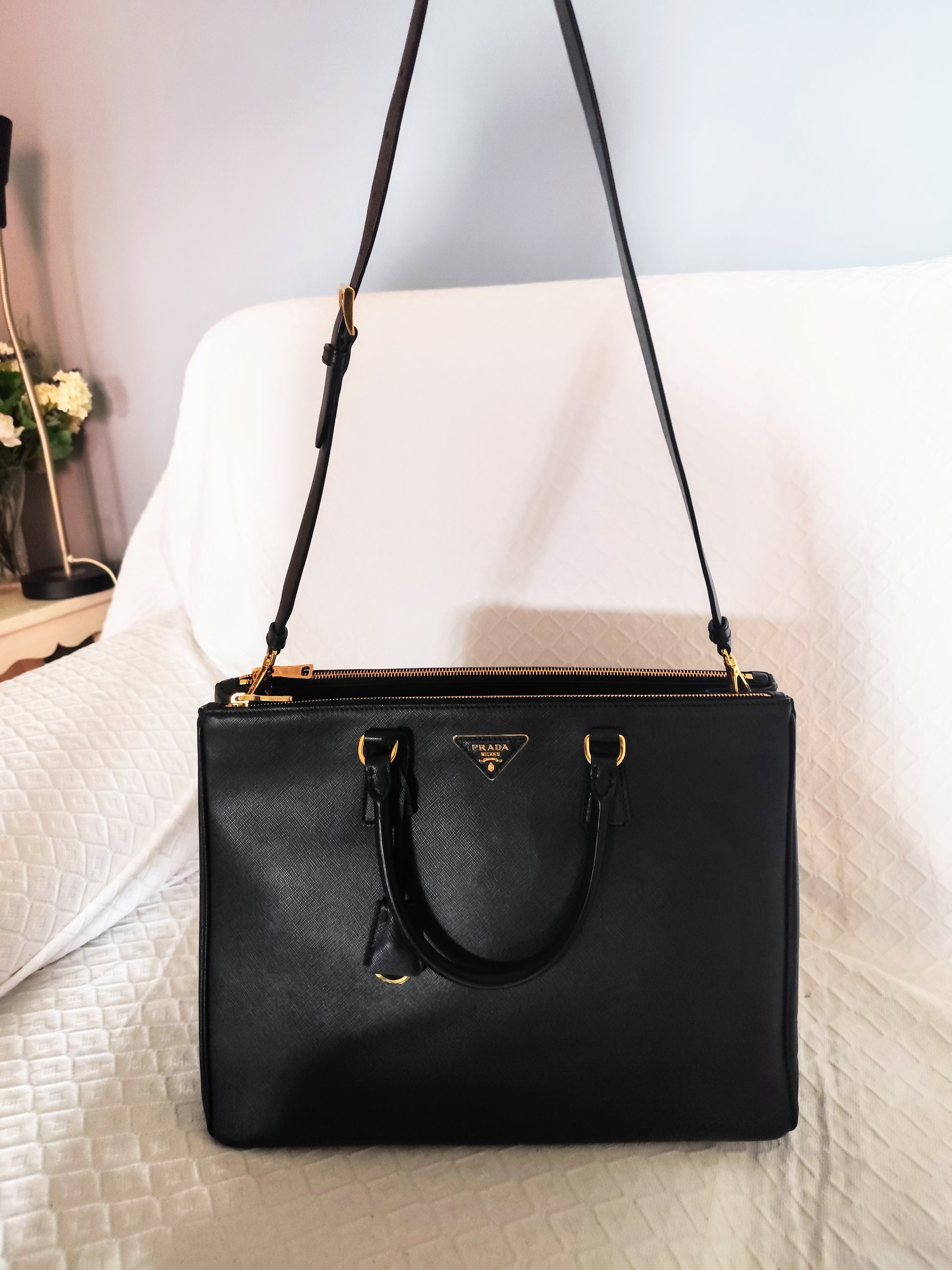 Vista frontale della borsa Prada Galleria XL in pelle nera con tracolla lunga e manici rigidi, finiture dorate